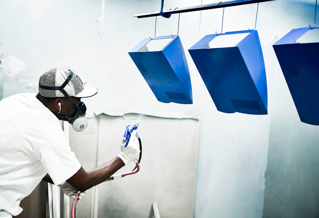 painted-sheet-metal-man-painting-blue-parts-hanging-gtr-manufacturing